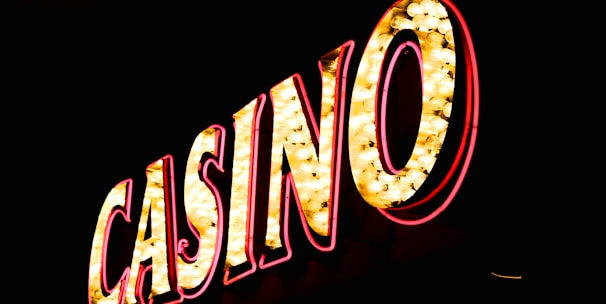 Brightly illuminated letters spell out 'CASINO' with glowing yellow bulbs and red outlines against a dark background.